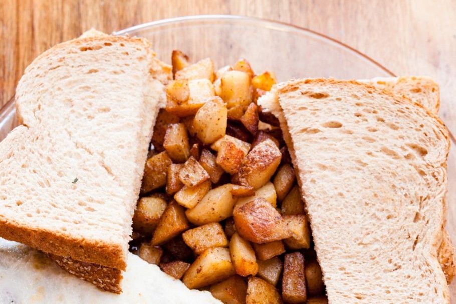 A close up of a sandwich with potatoes on a plate.