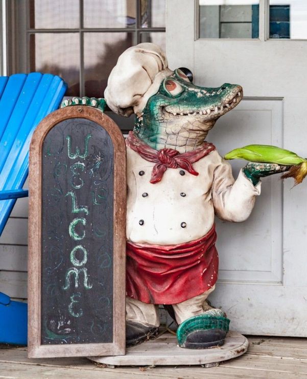 A statue of a chef alligator holding a tray of food