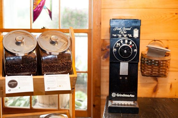 A coffee grinder is sitting on a table next to a shelf of coffee beans.