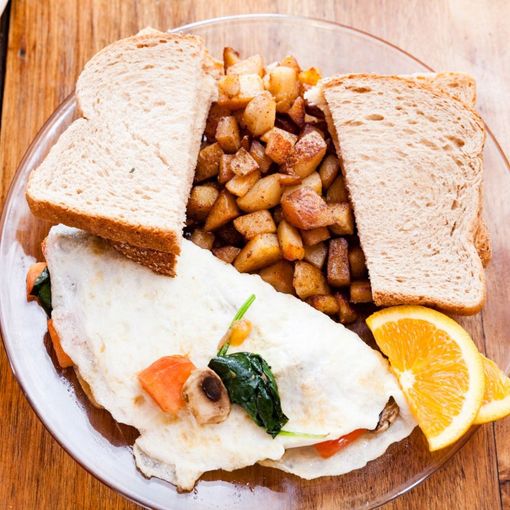 A plate of food with eggs potatoes and a slice of orange