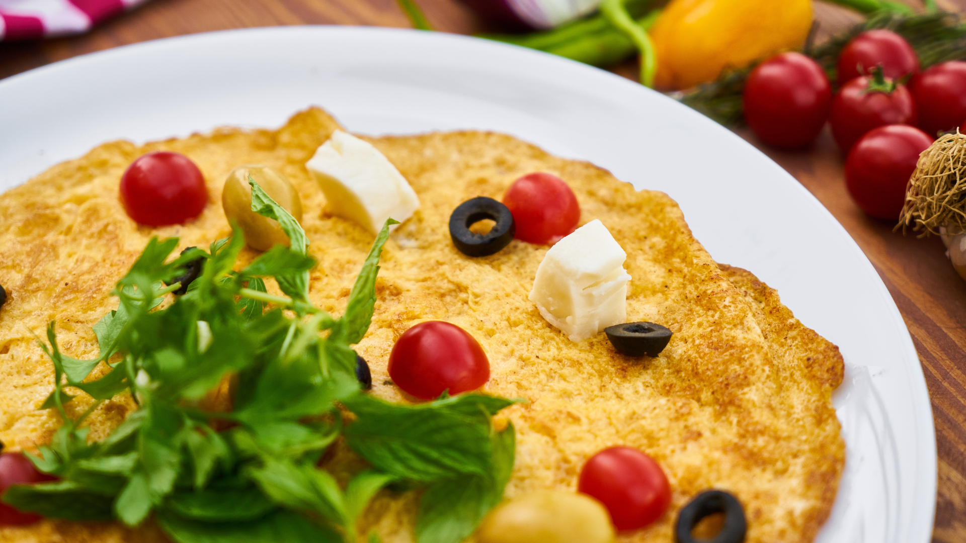 A white plate topped with a pizza with tomatoes , olives and cheese.