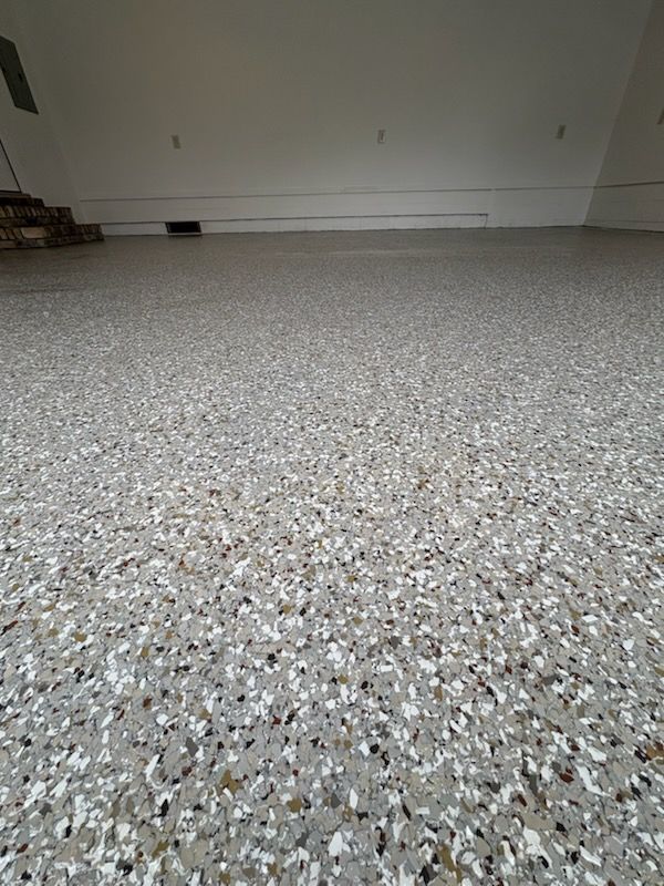 Garage floor with epoxy coating, speckled with gray, white, and black chips.