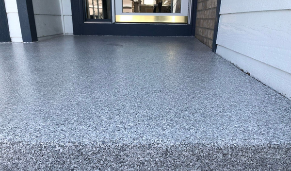 A person uses a trowel to apply yellow epoxy to a brown surface, creating a smooth layer.