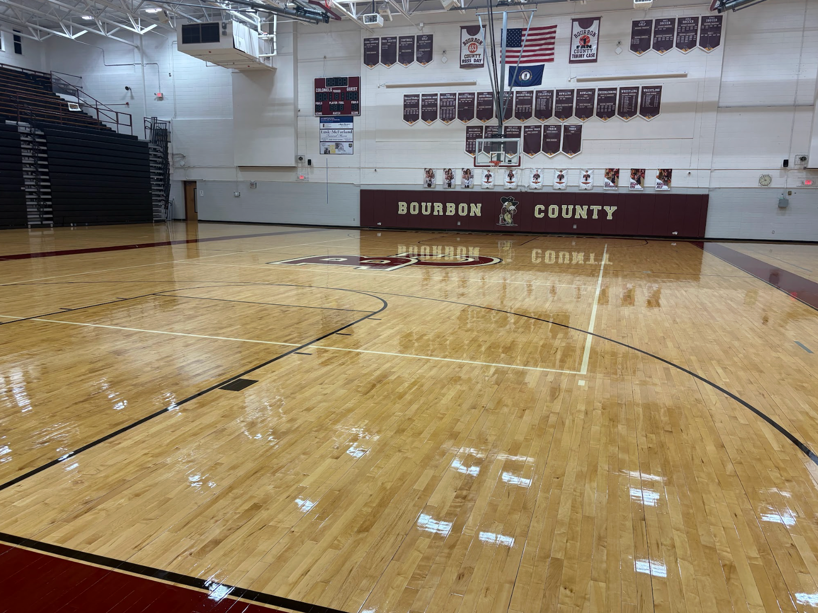 Person applying finish to a wooden herringbone floor with a roller. Indoors, paint can, and respirator visible.