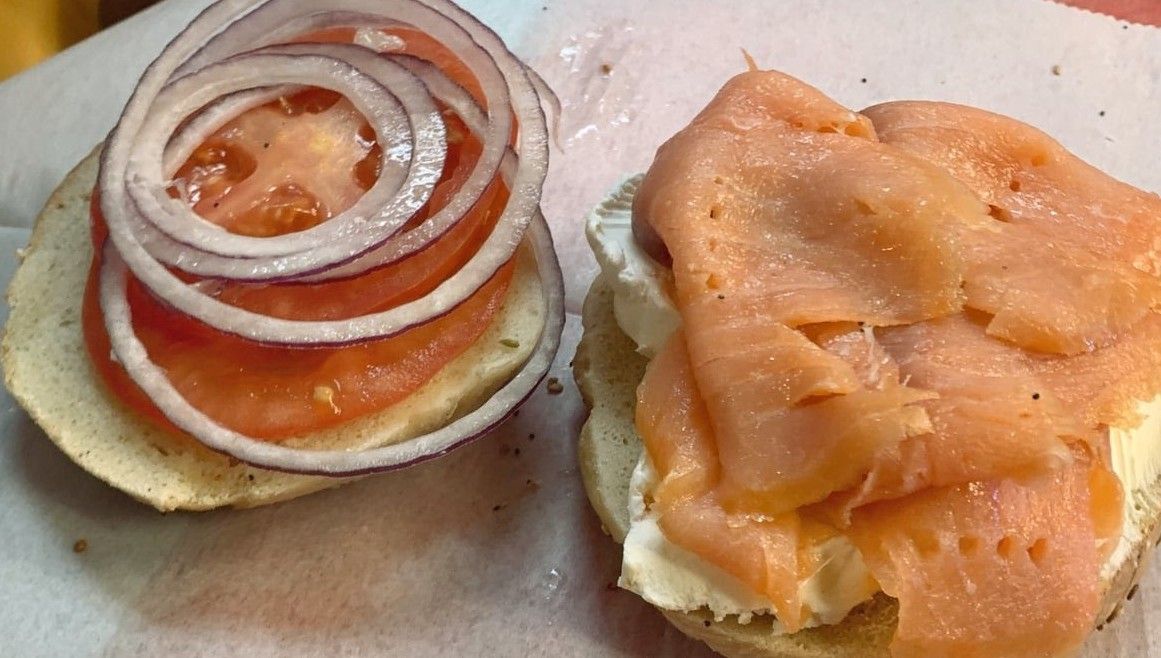 A bagel with smoked salmon , tomatoes and onions on it