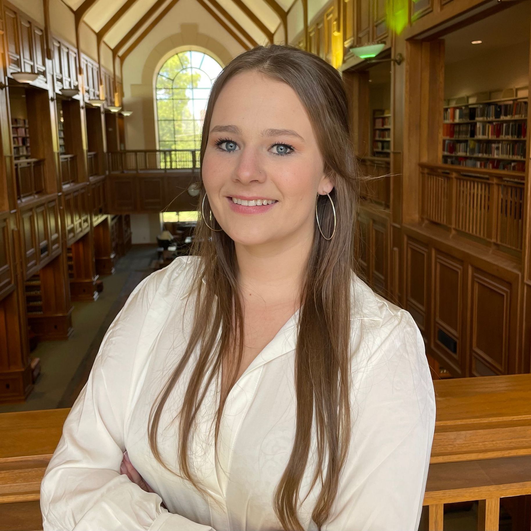 A woman in a white shirt is smiling in a library