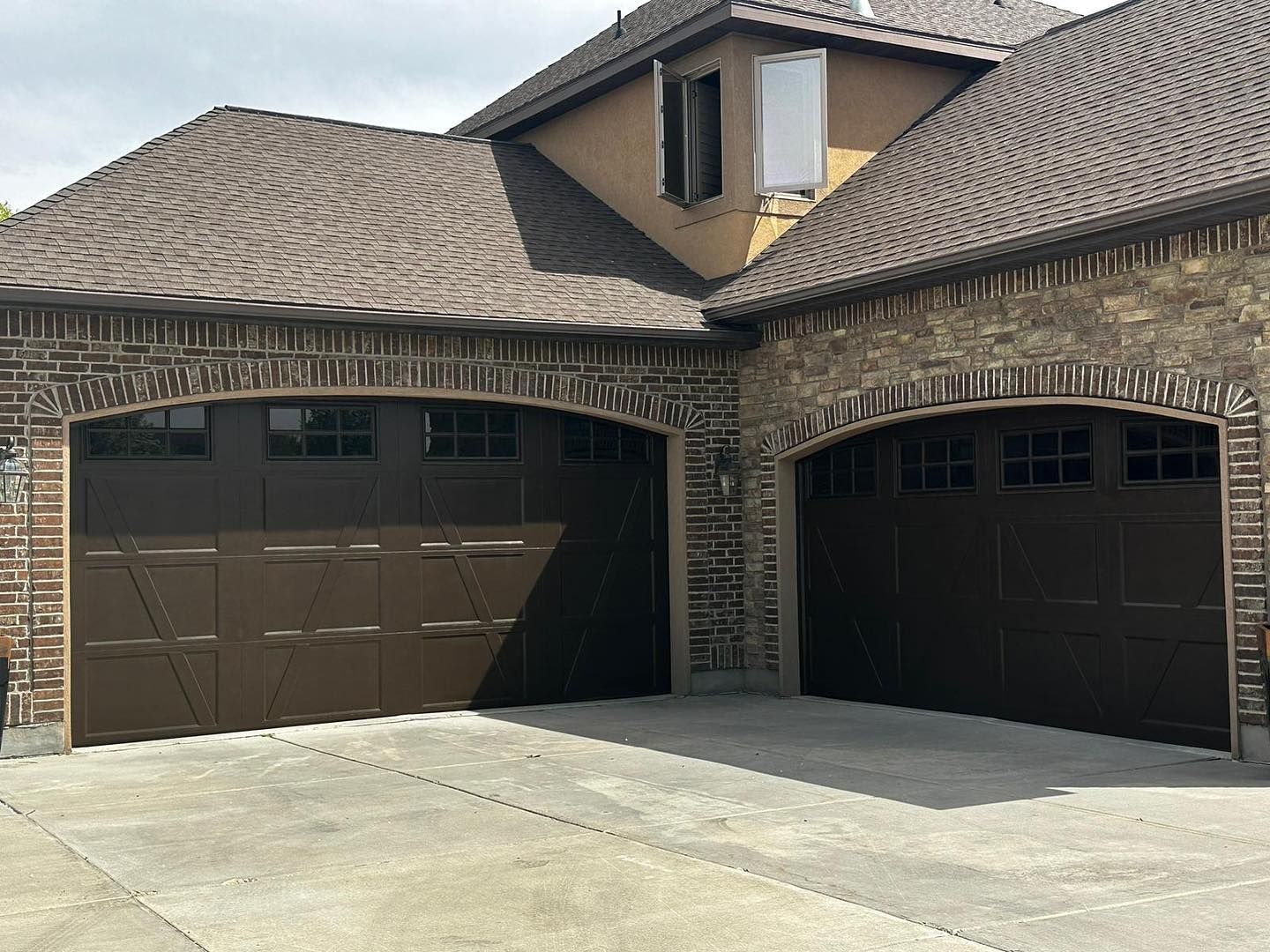 There are two garage doors on the side of a house.