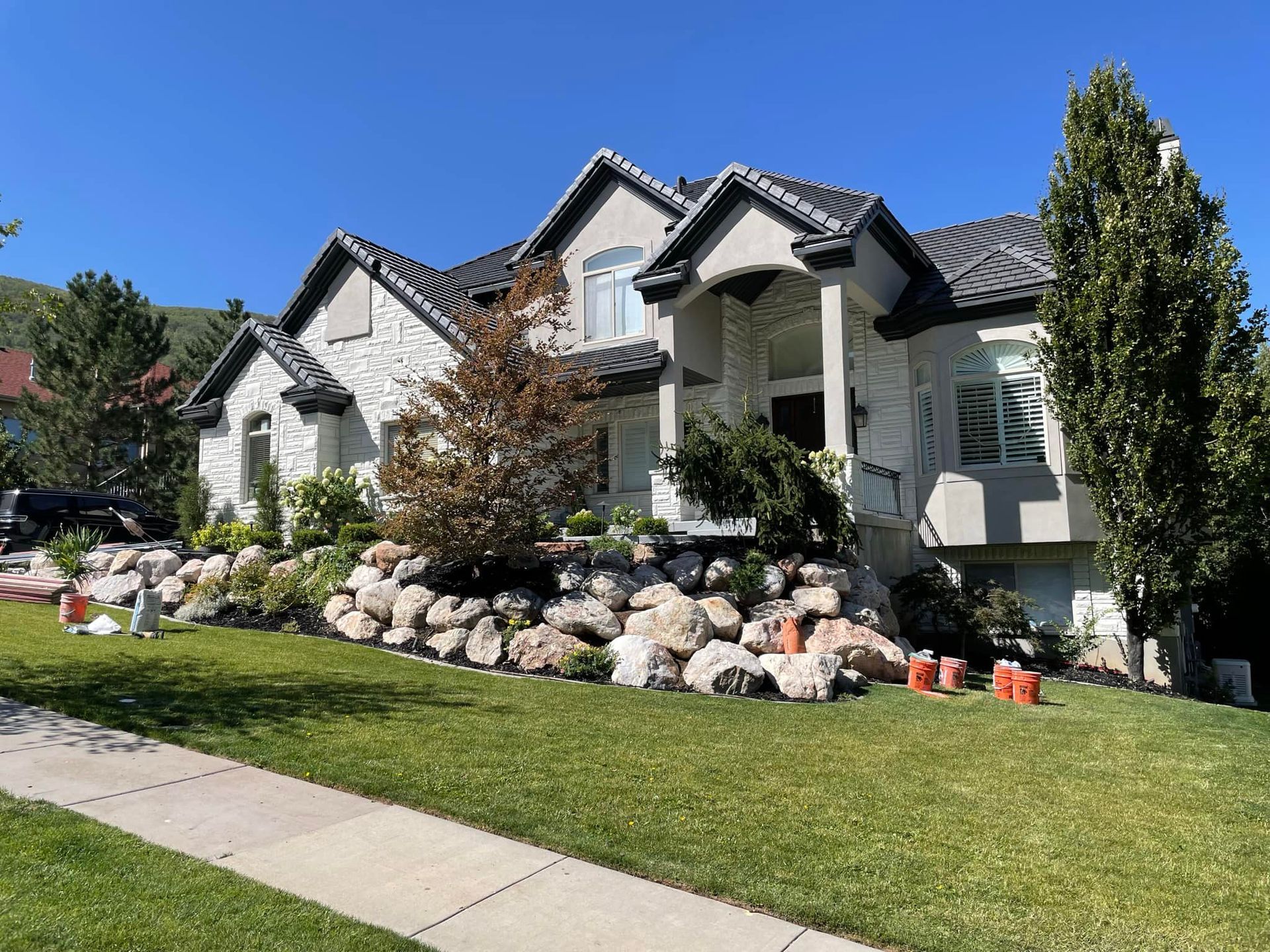 A large white house with a black roof is sitting on top of a lush green lawn.