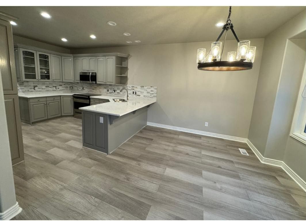 A kitchen and dining room in a house with a chandelier hanging from the ceiling.