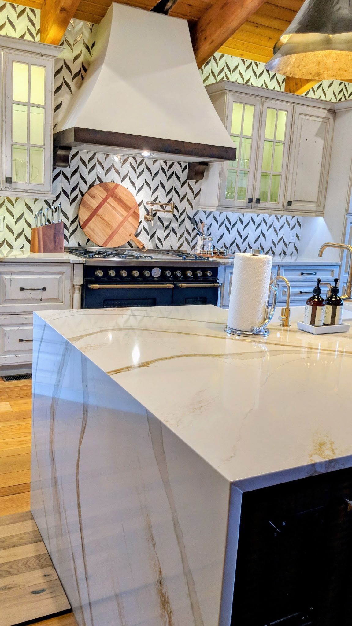 Kitchen with white quartz countertop, black oven, and chevron backsplash.