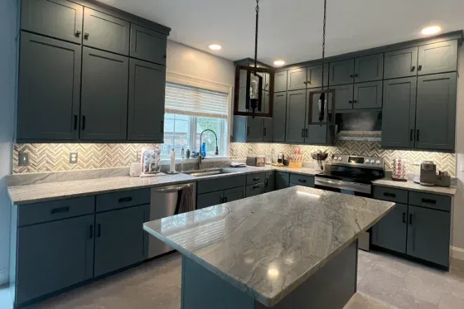 A kitchen with gray cabinets and a large island in the middle.