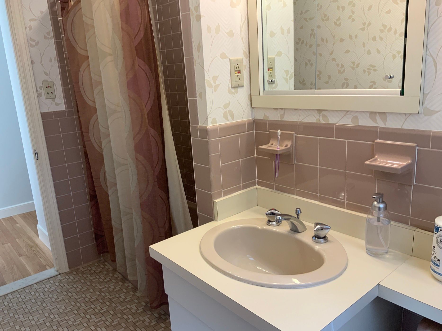 A bathroom with a sink , mirror and shower curtain