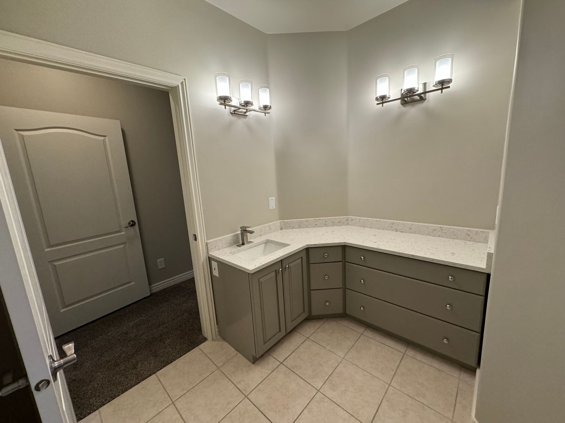 A bathroom with a sink , dressers , and a door.