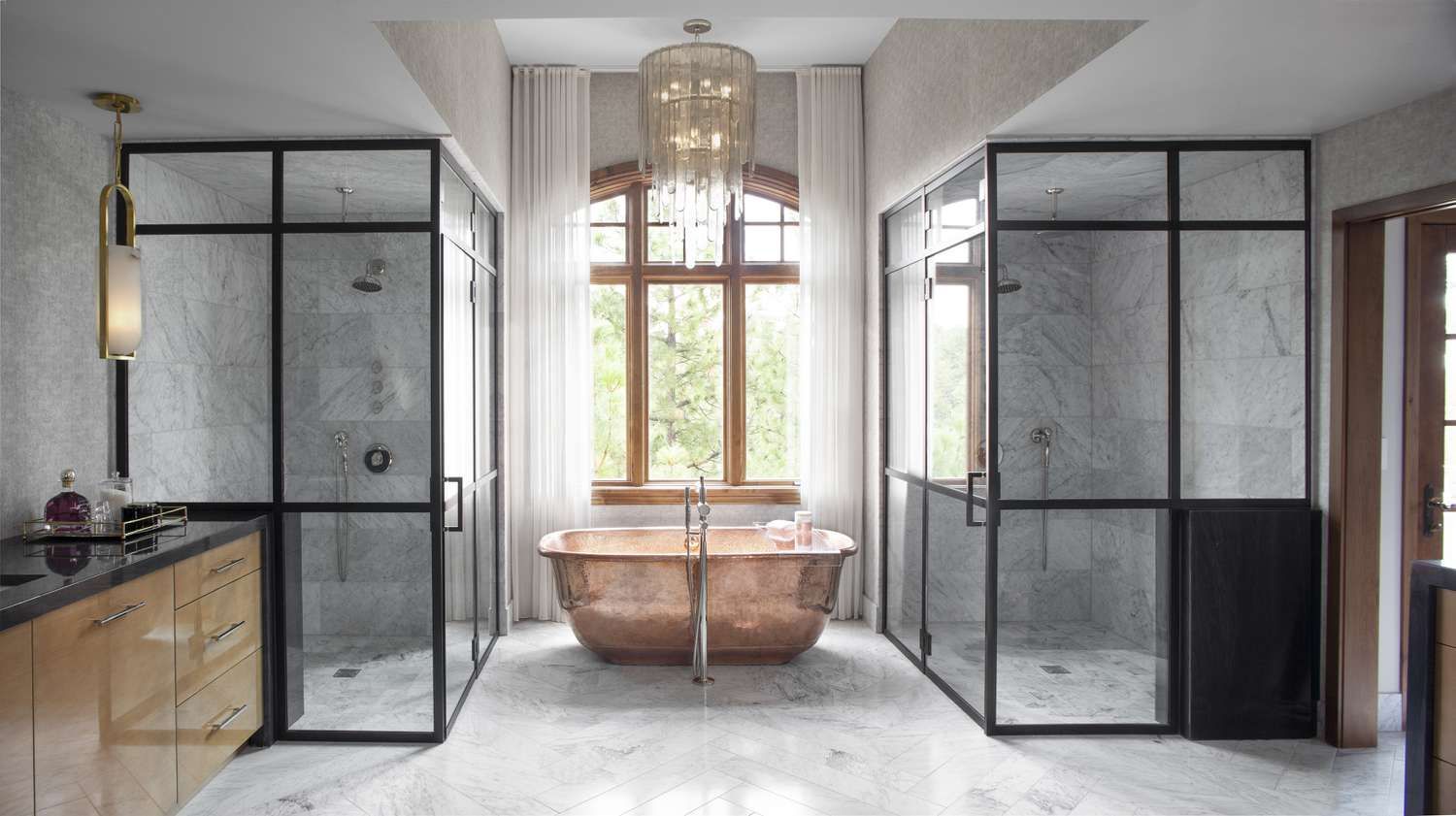 Luxurious bathroom with copper tub, two glass showers, and a large window.