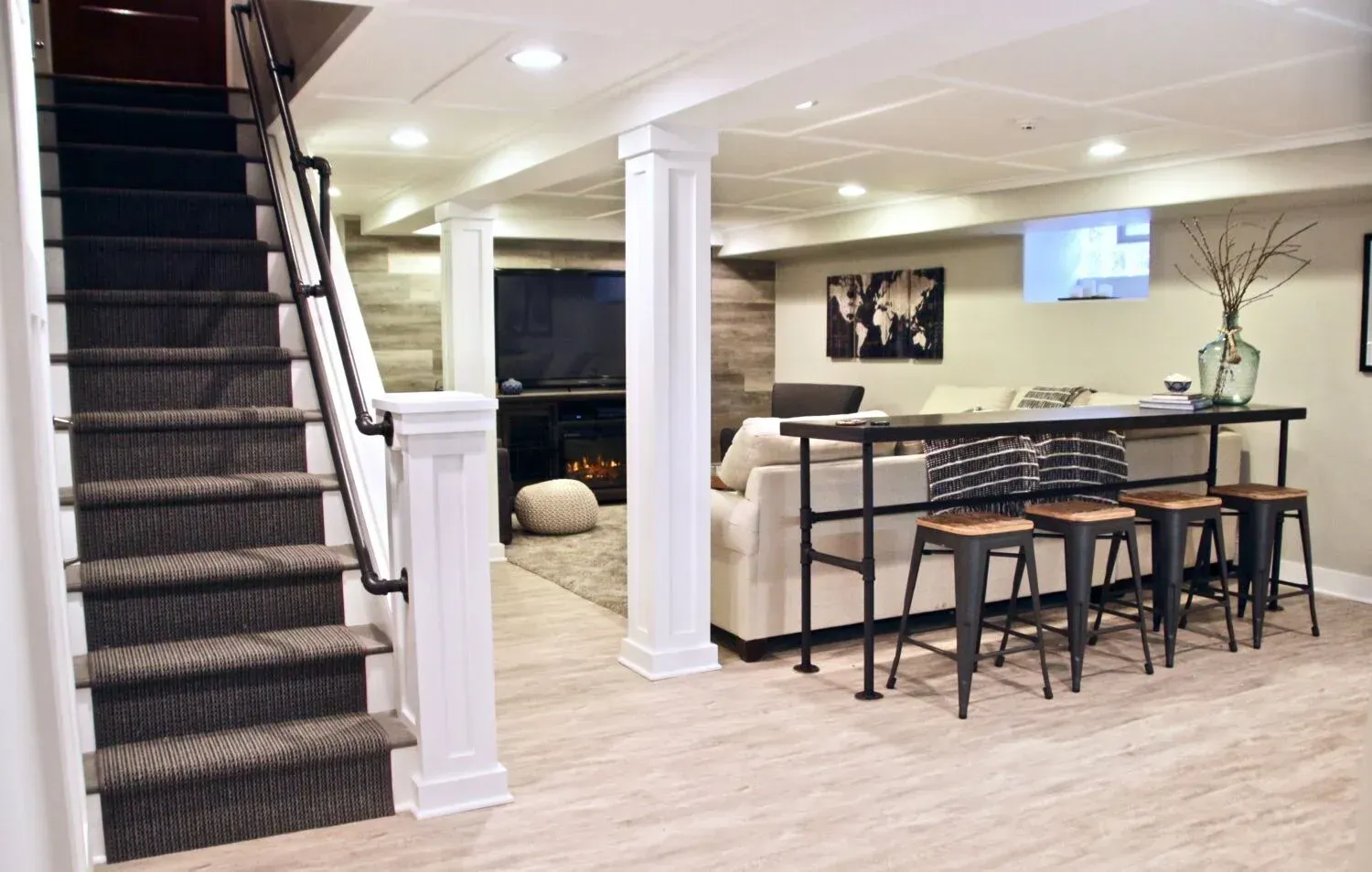 A basement with stairs leading up to the second floor and a bar.