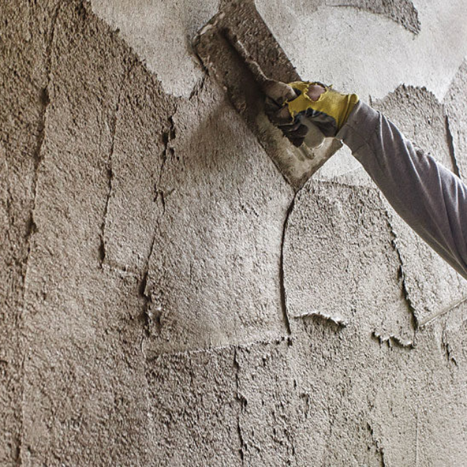 A person wearing yellow gloves is plastering a wall