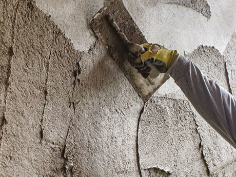 A person is plastering a wall with a trowel.