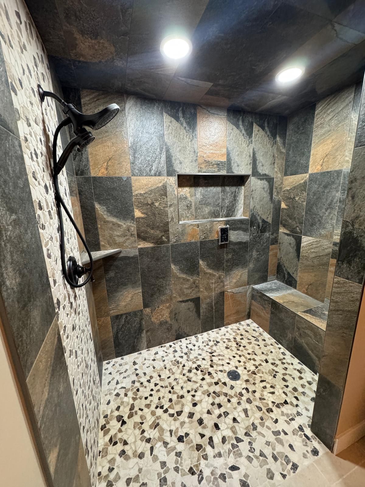 A bathroom with a walk in shower and a bench.