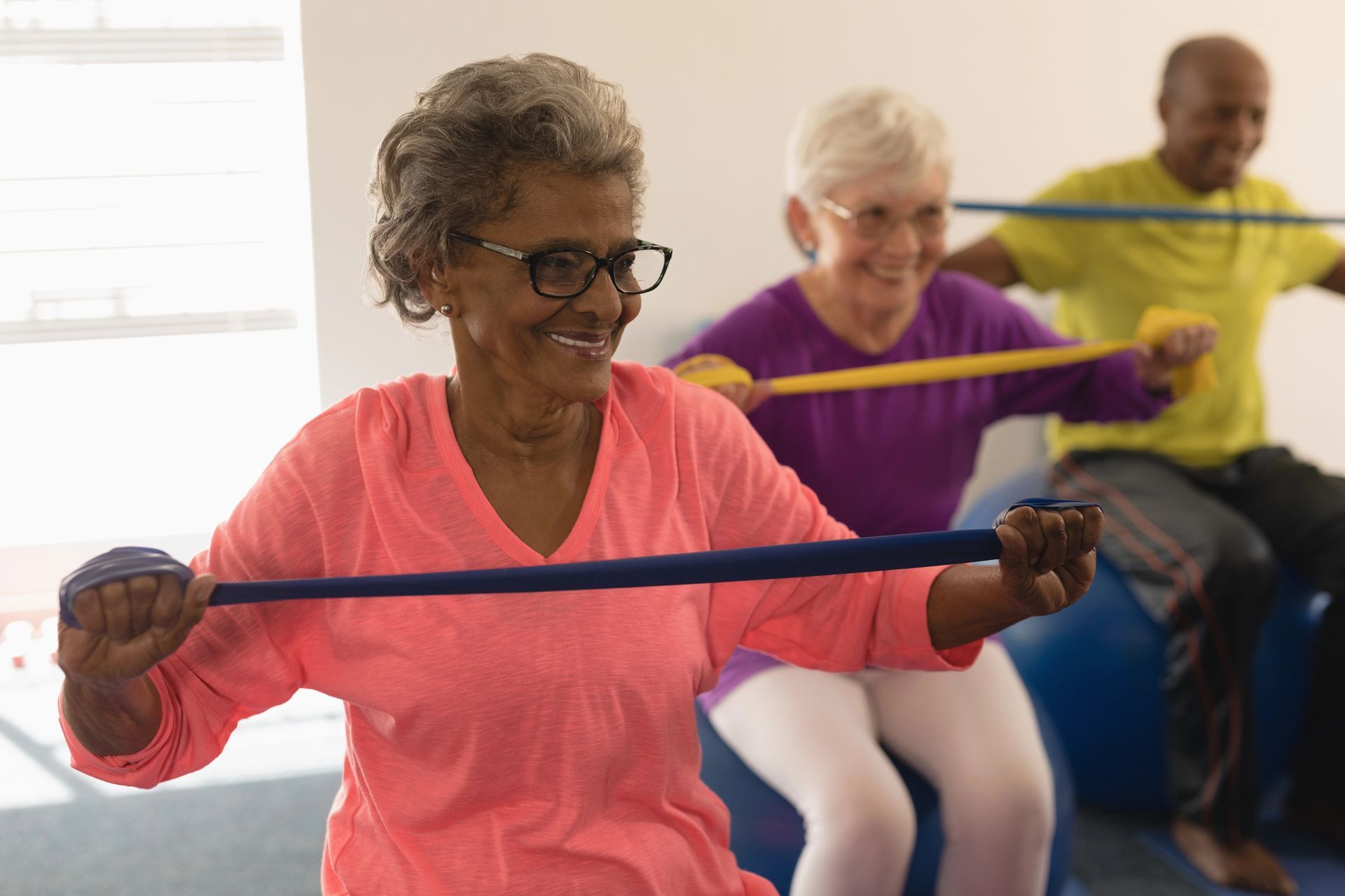 diverse group of medicare age people working out with stretchy bands while balance on yoga ball