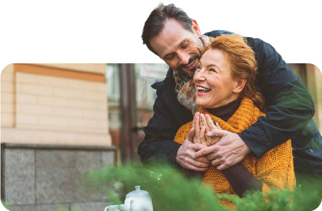 A senior man is hugging a senior woman while sitting at a table.