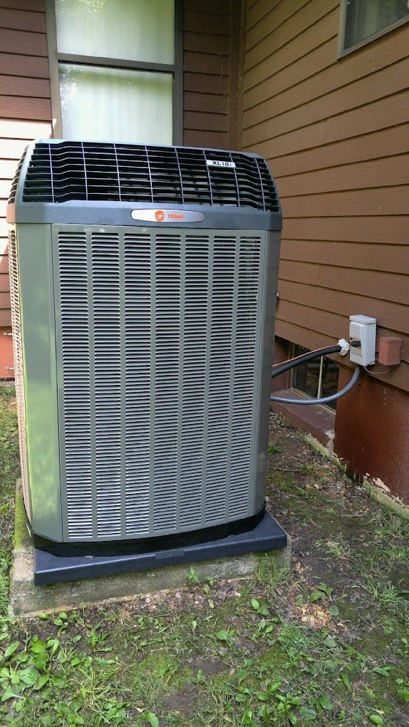 A large air conditioner is sitting on the side of a house.