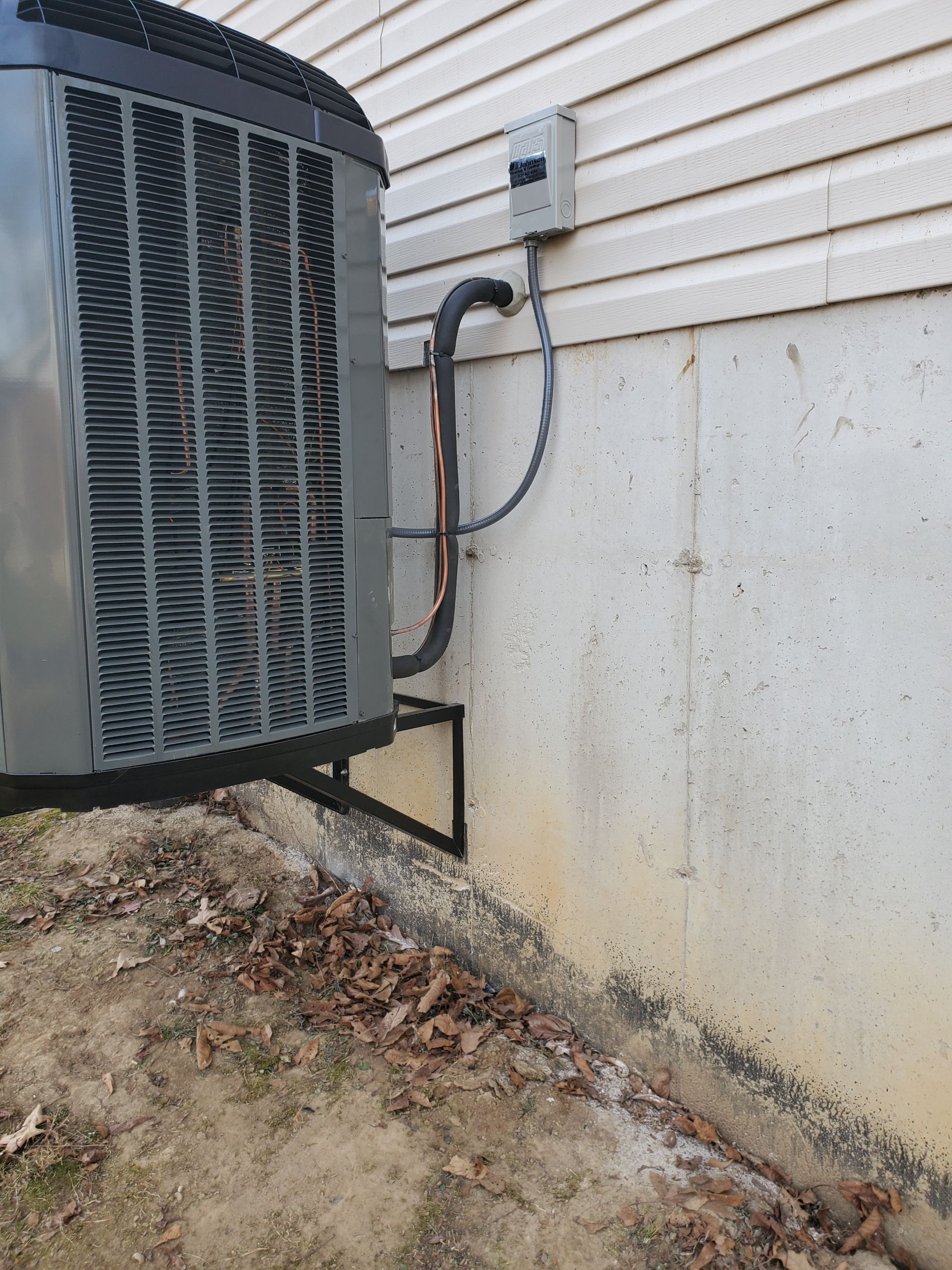 An air conditioner is attached to the side of a house.