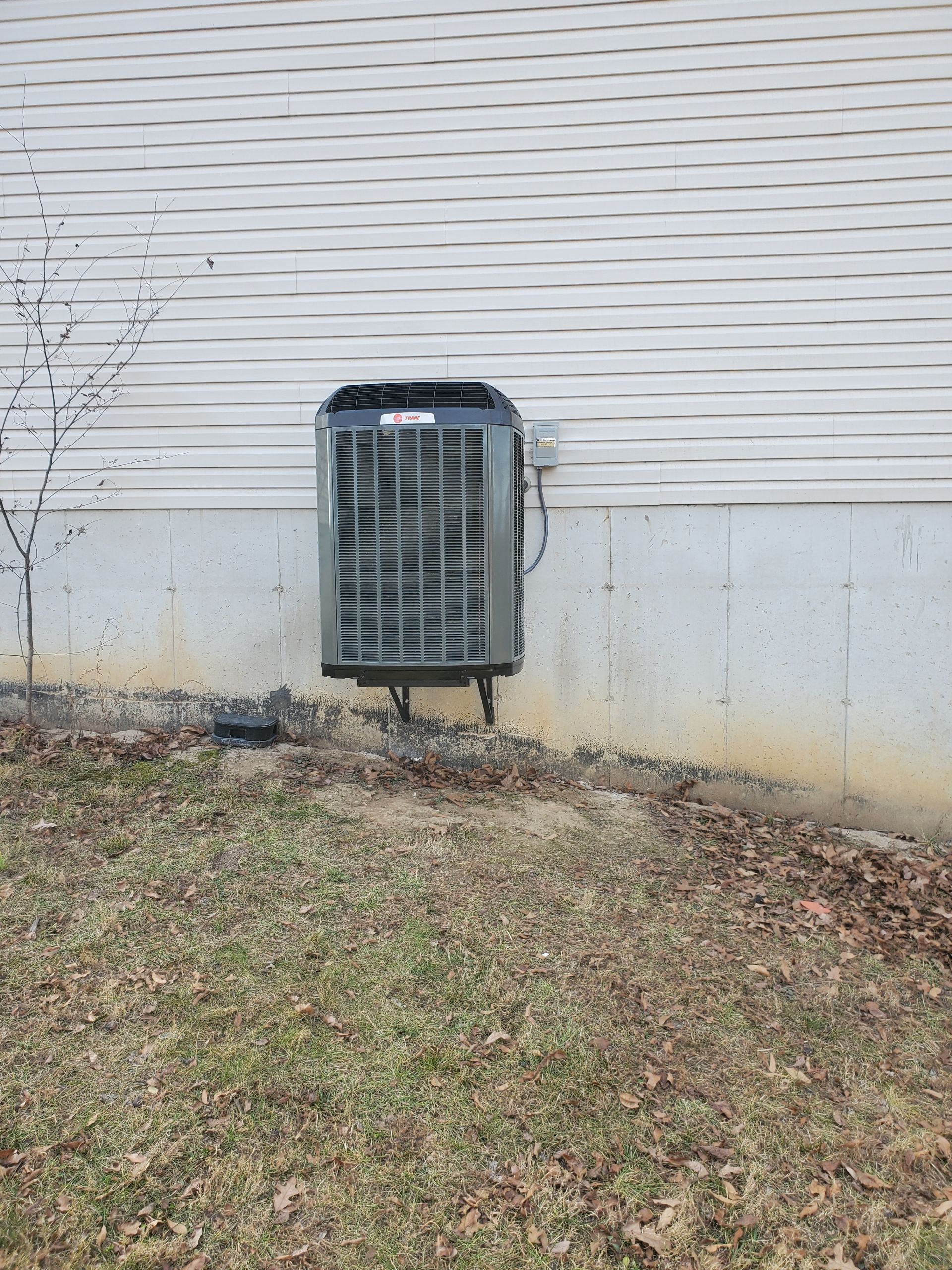 An air conditioner is mounted on the side of a house.