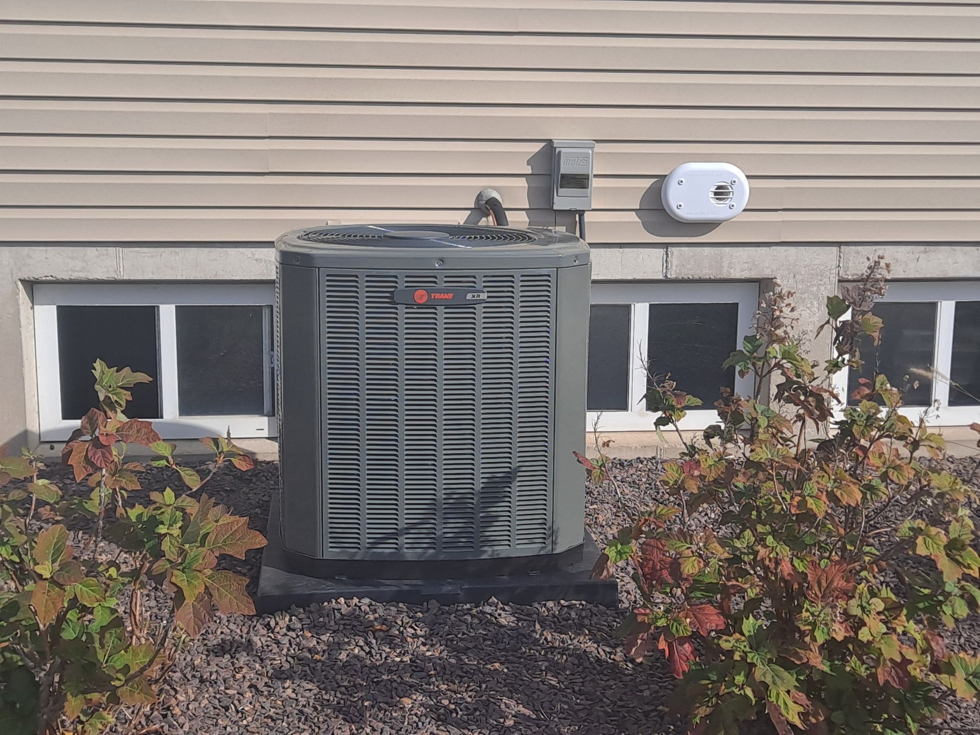 An air conditioner is mounted on the side of a house.