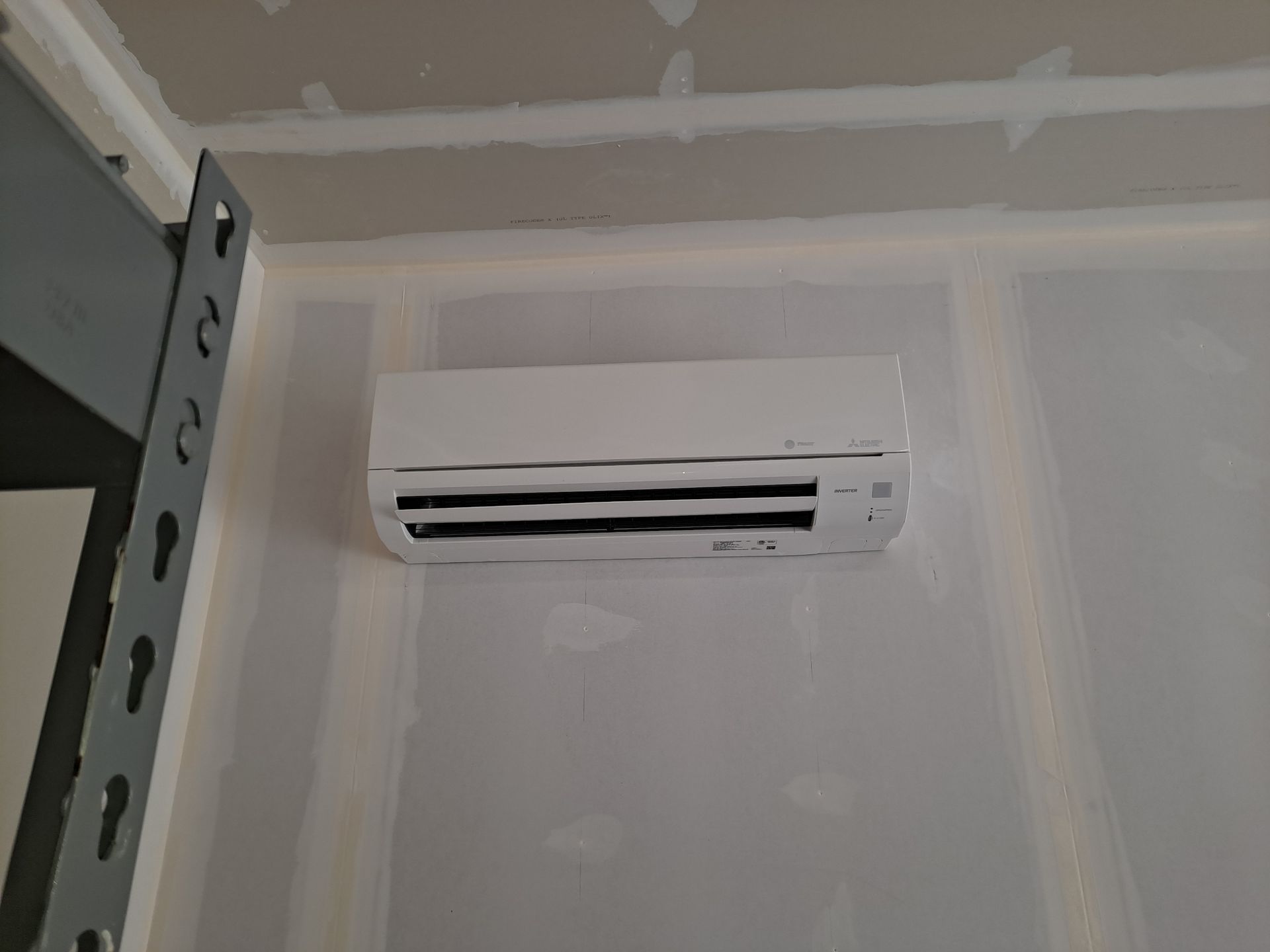 A white air conditioner is hanging on a wall in a room. mini-split