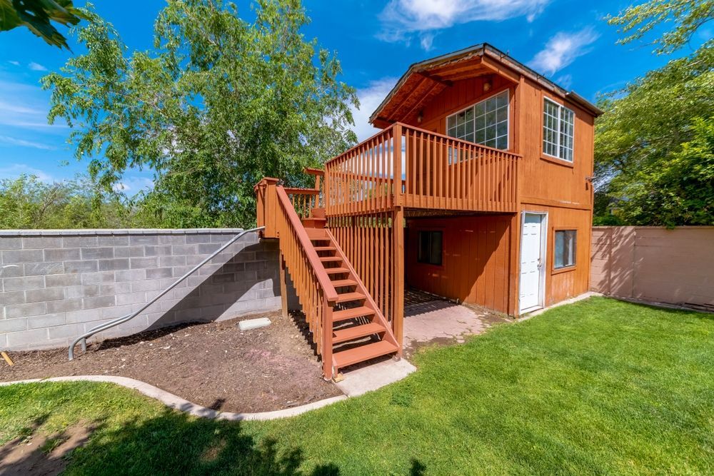 A wooden house with a deck and stairs in the backyard.