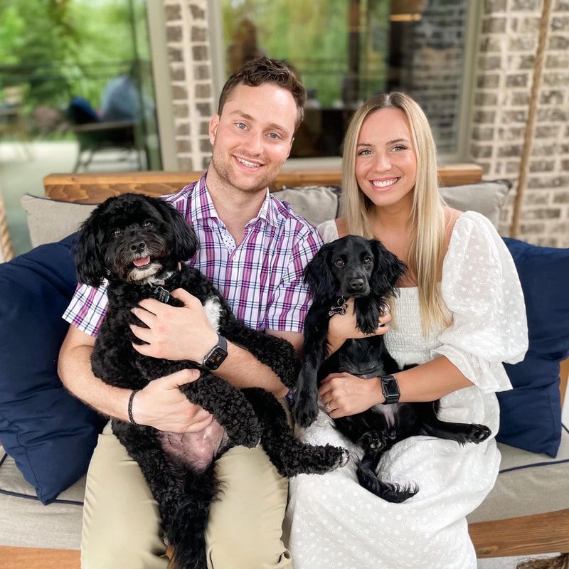 A man and a woman are sitting on a couch holding two dogs.