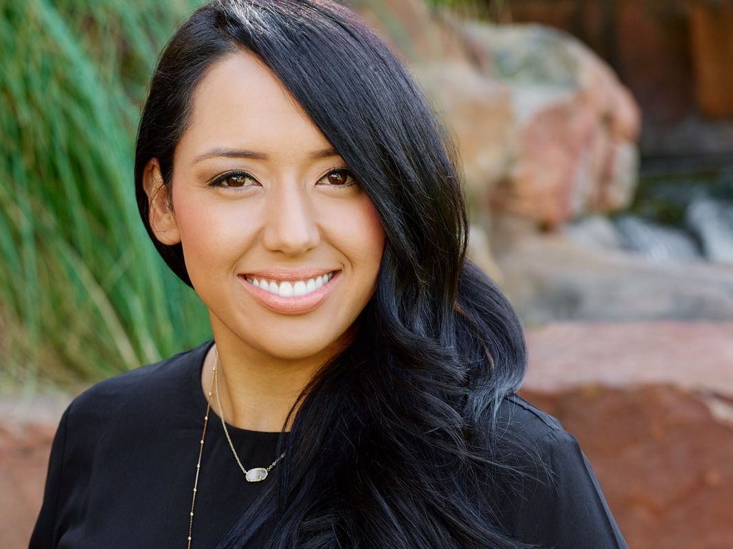 A woman with long black hair is smiling for the camera.