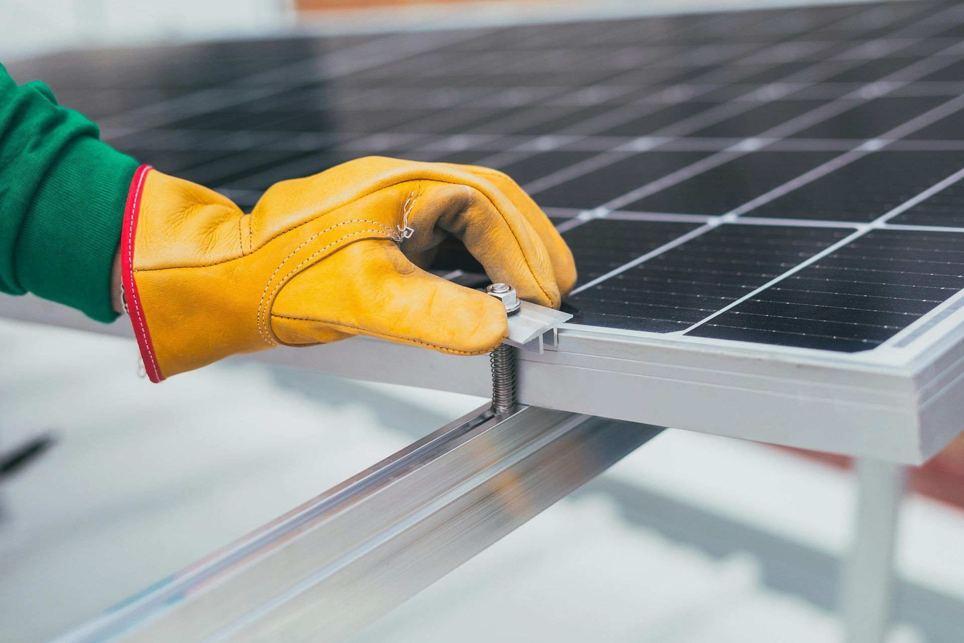 Person in work gloves securing a solar panel to a metal frame.