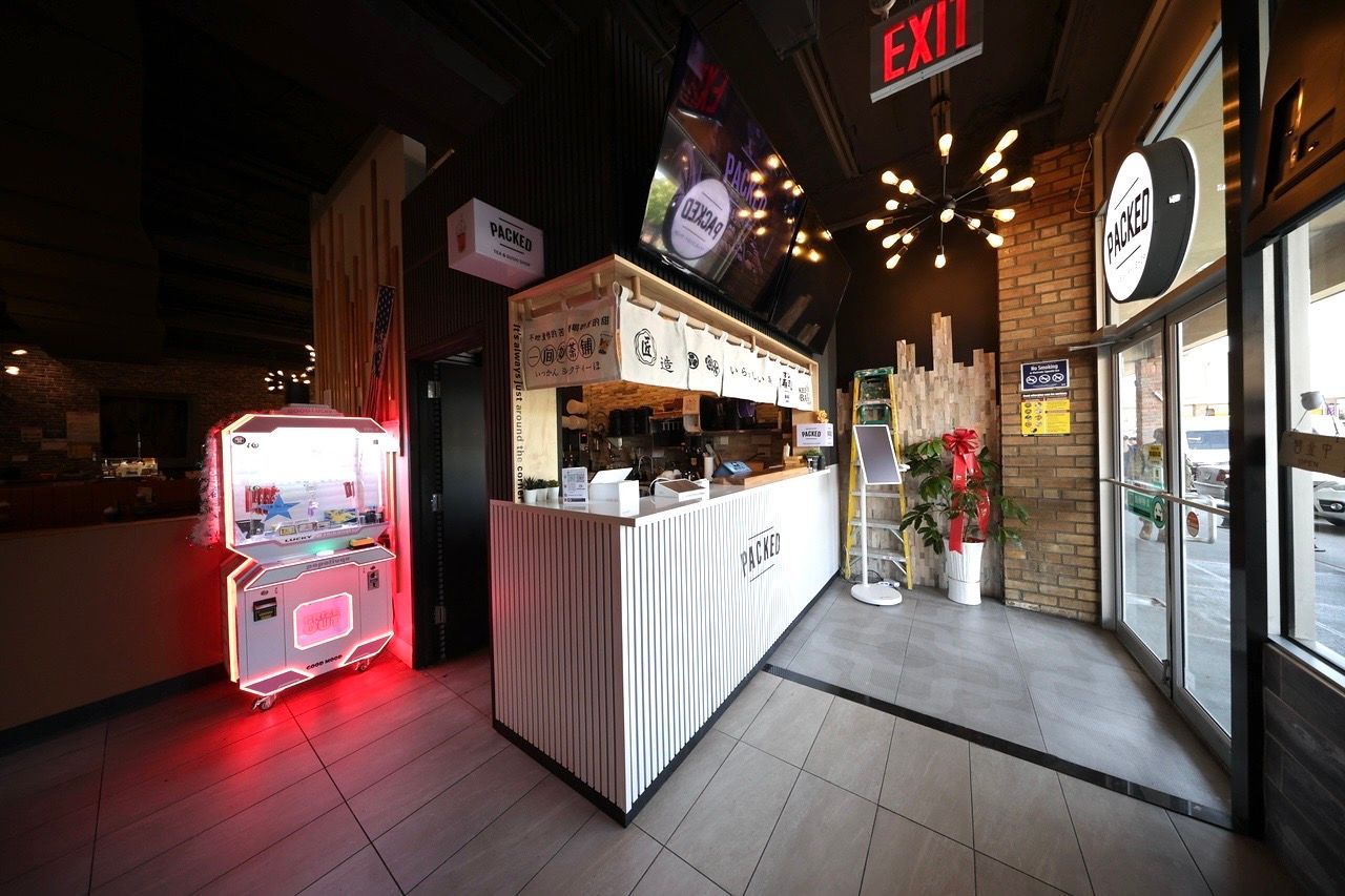 Dim café entry with white counter, neon lights, and glass doors at night