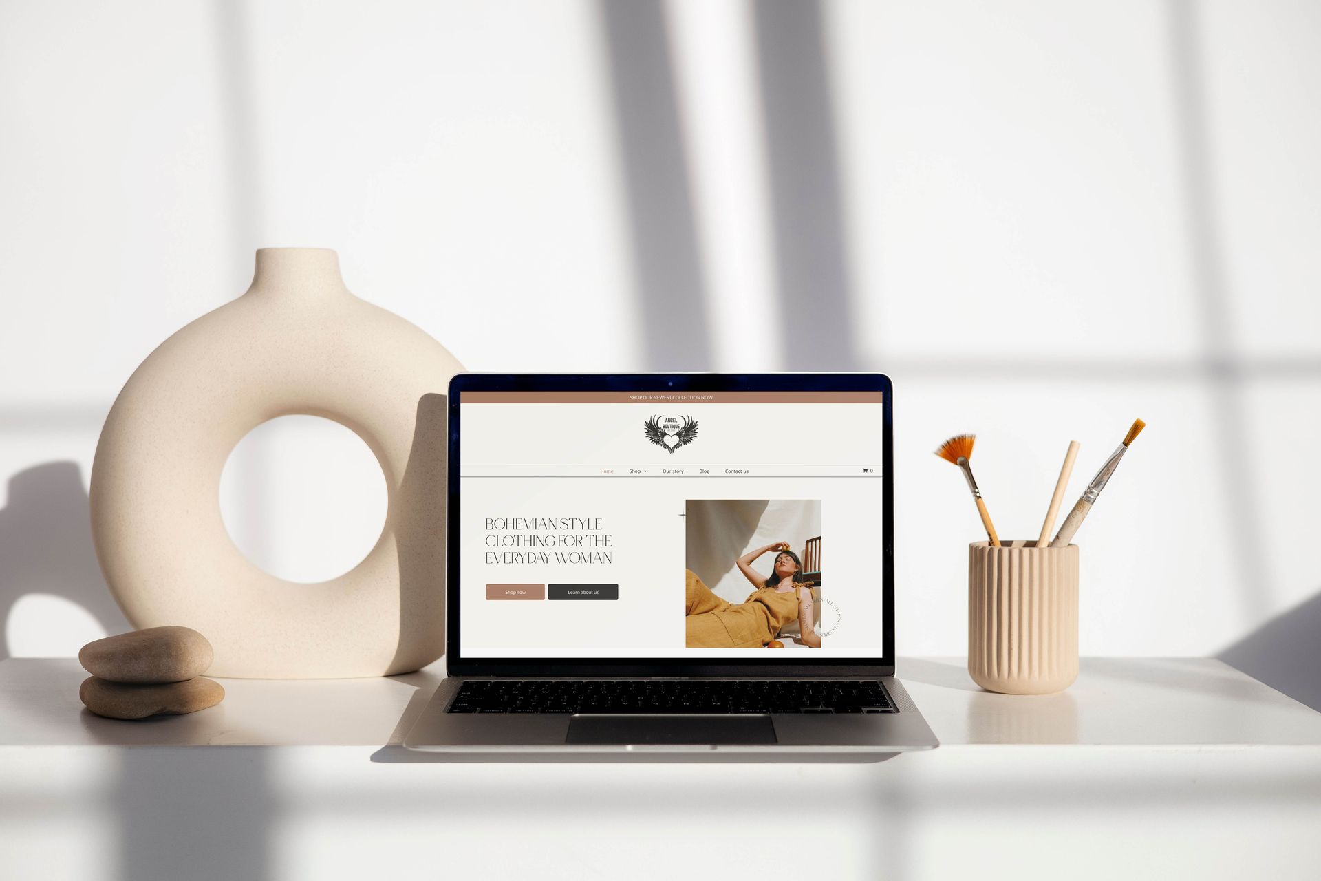 Laptop displaying bohemian-style clothing website for everyday women, with minimalist decor and natural light