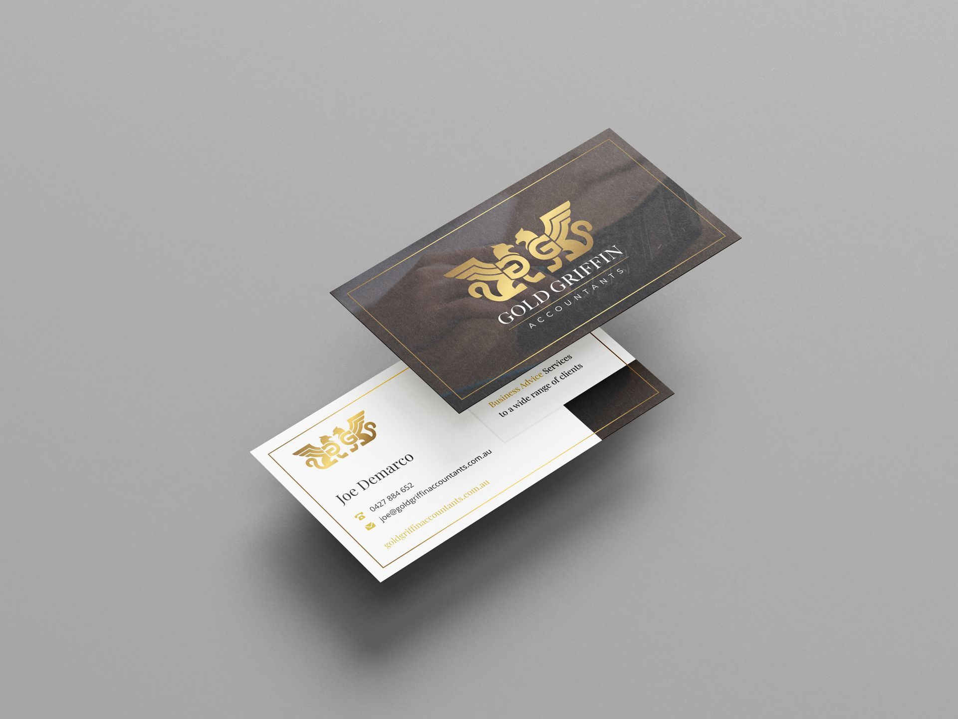 Two business cards are floating in the air on a gray surface.