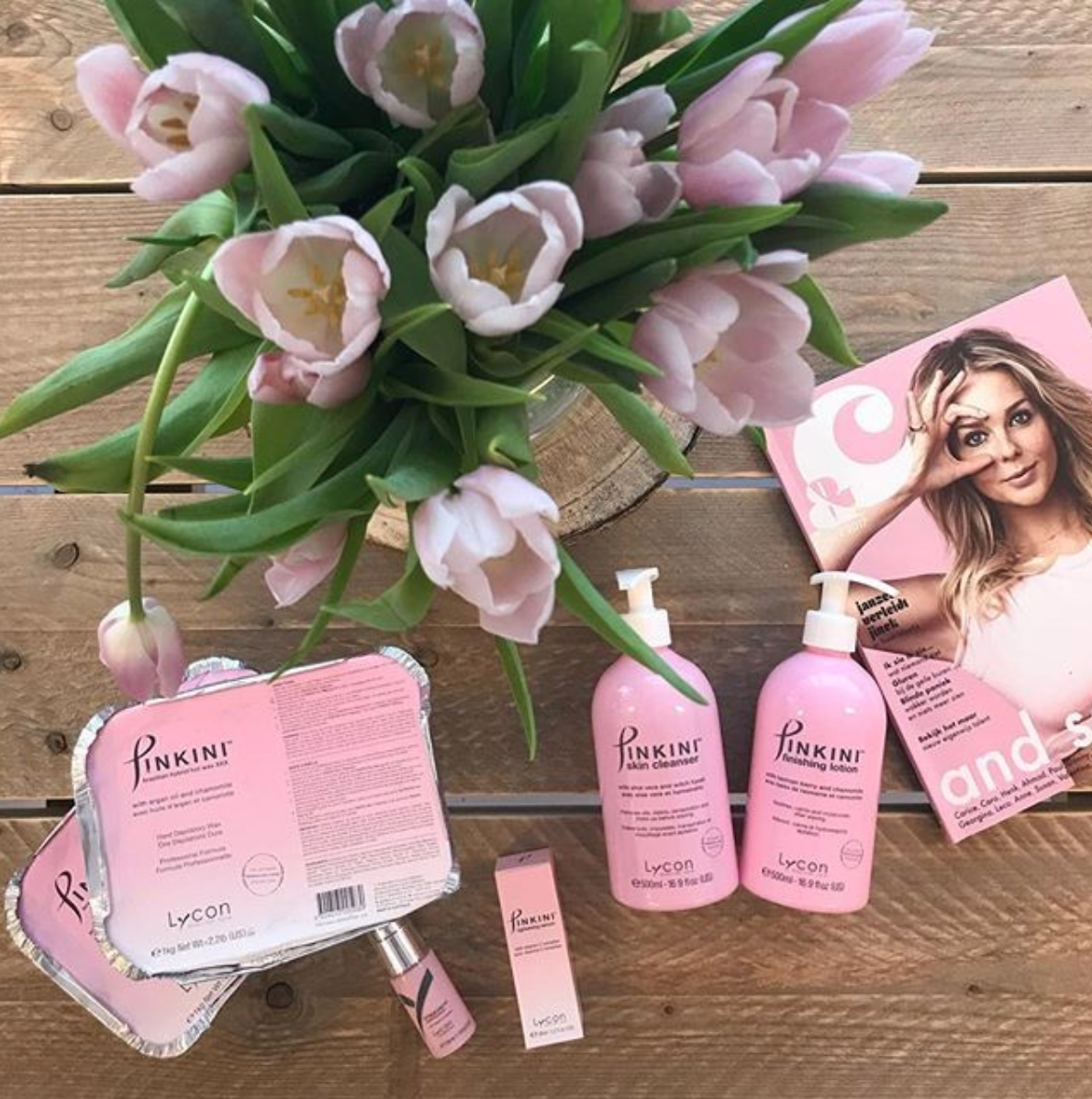 A bouquet of pink flowers sits on a wooden table
