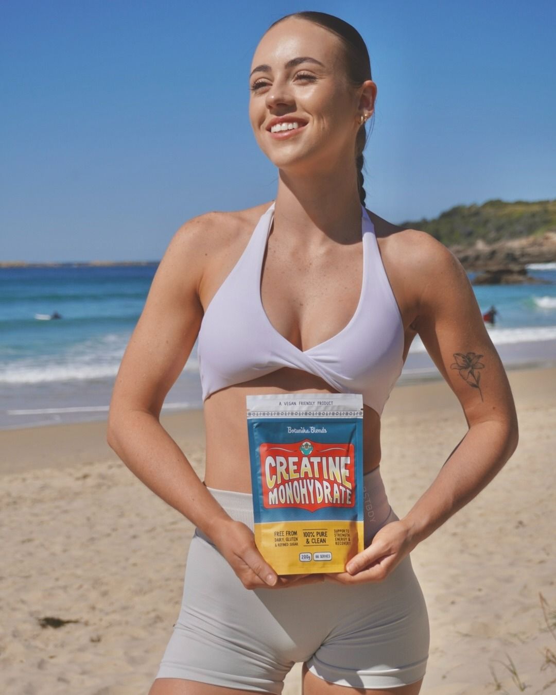 A woman is holding a bag of creatine on the beach.