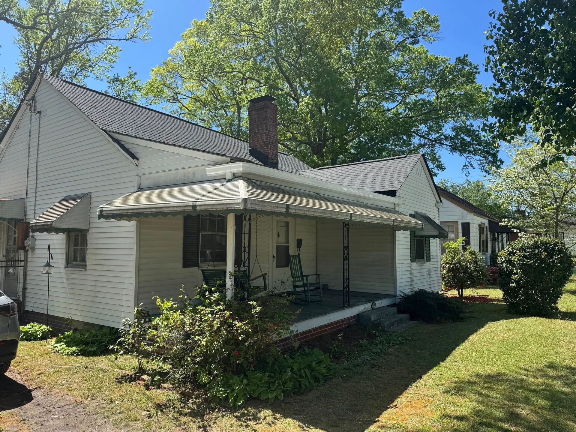 A white house with a porch and a car parked in front of it.