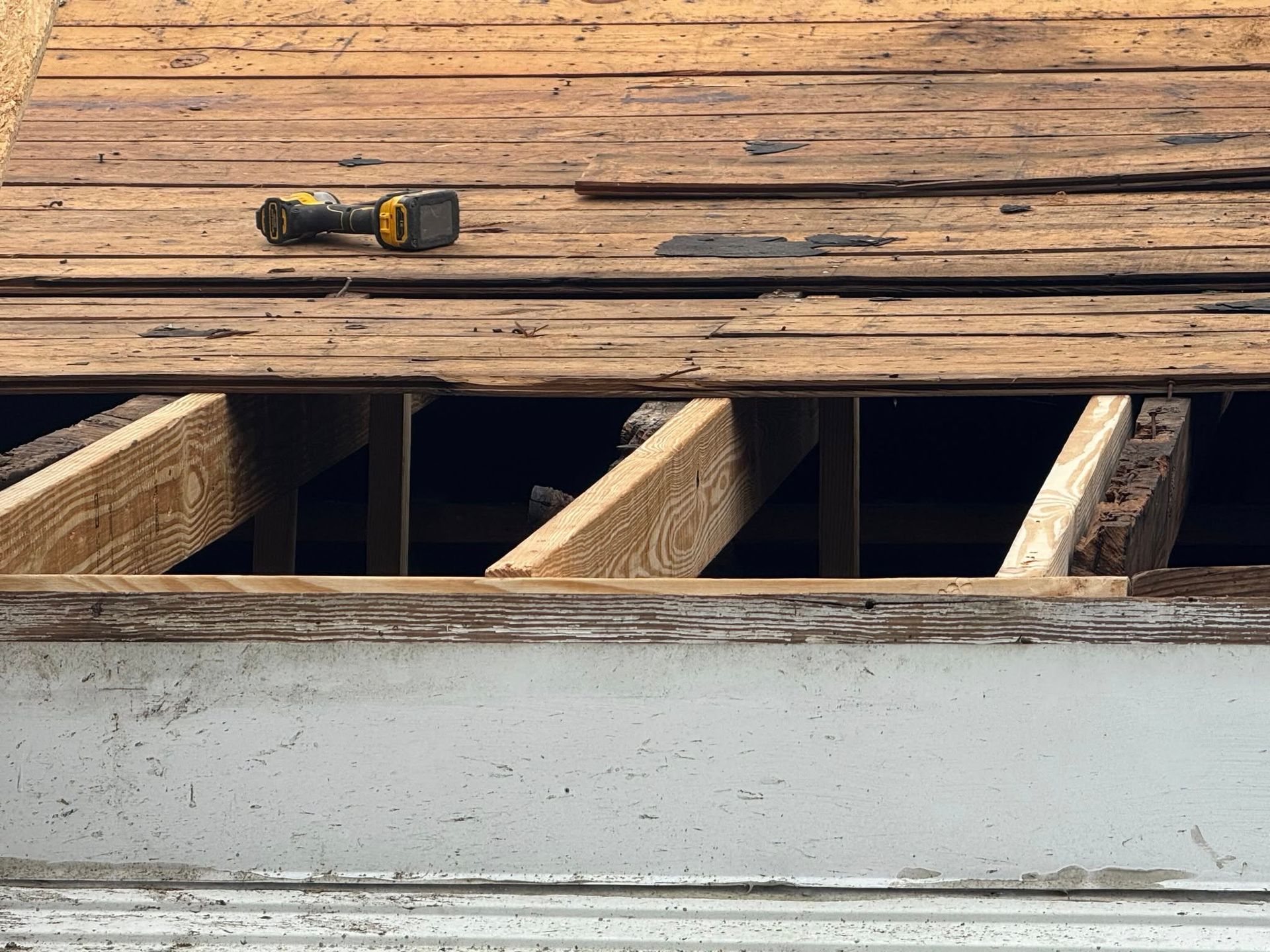 A drill is sitting on top of a wooden floor.