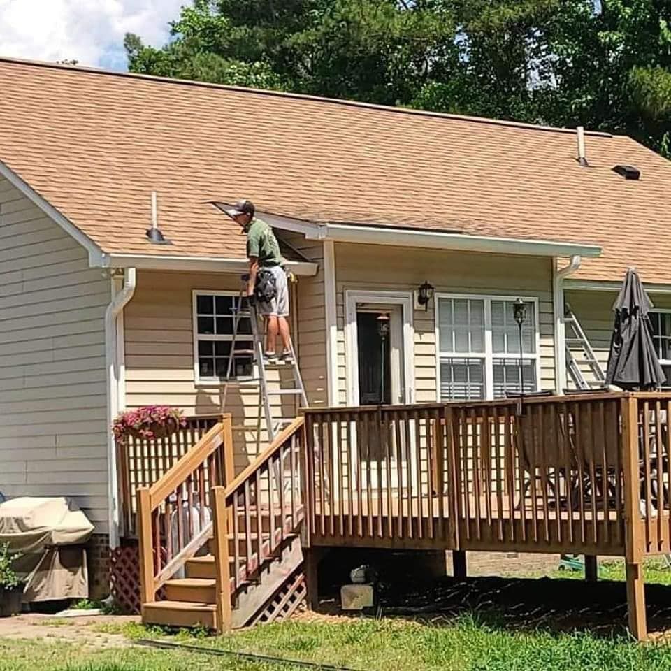 A man is standing on a ladder on the roof of a house.