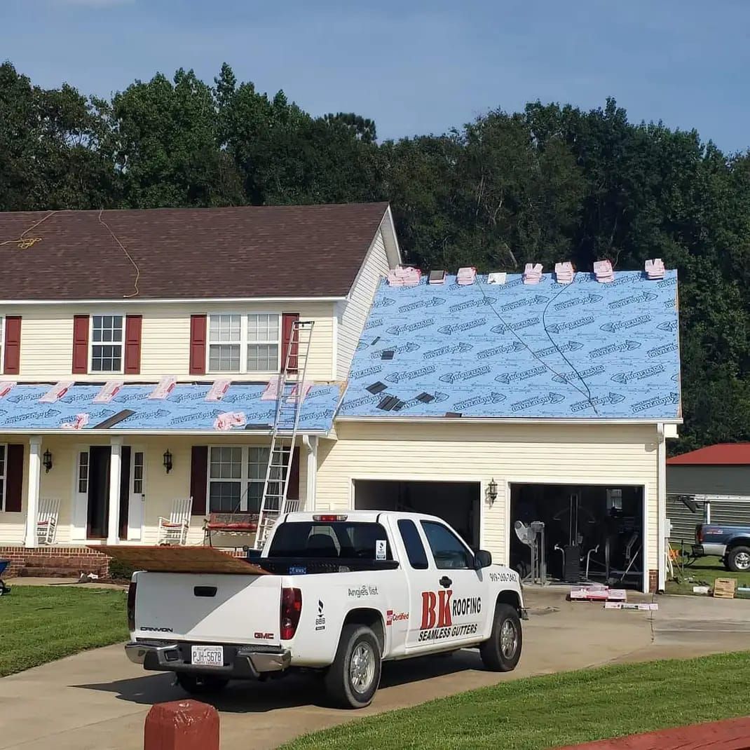 A white truck is parked in front of a house that is being remodeled.