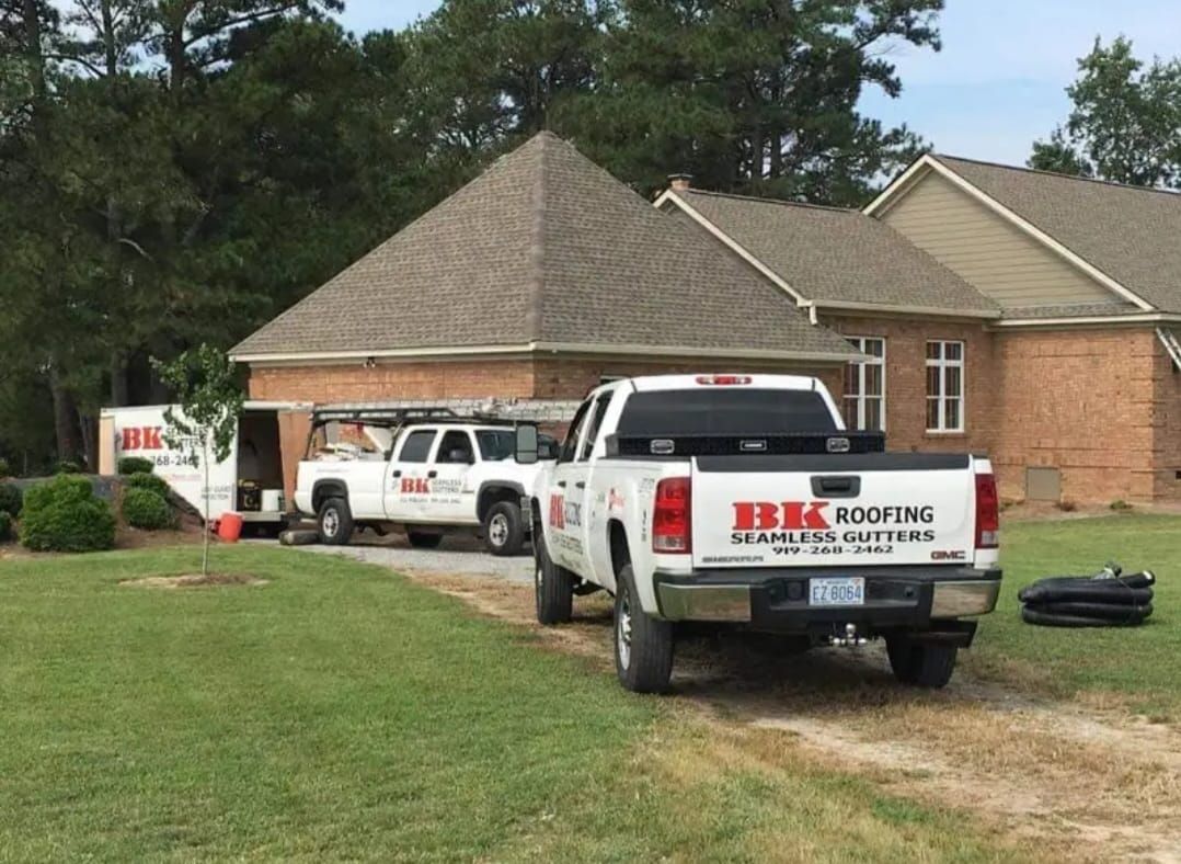 Two trucks are parked in front of a brick house.