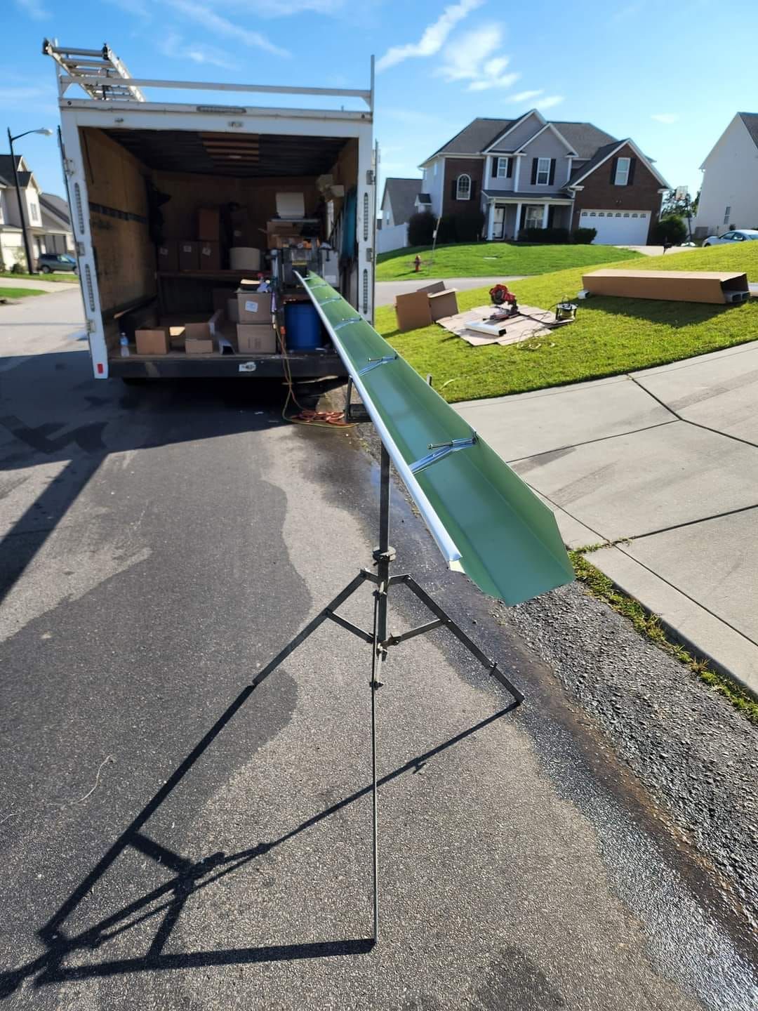 A white truck is parked on the side of the road next to a green pipe on a stand.