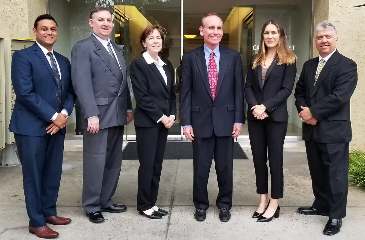 Six people in business attire standing outside a building.