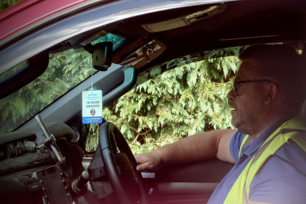 A man in a yellow vest is driving a car.