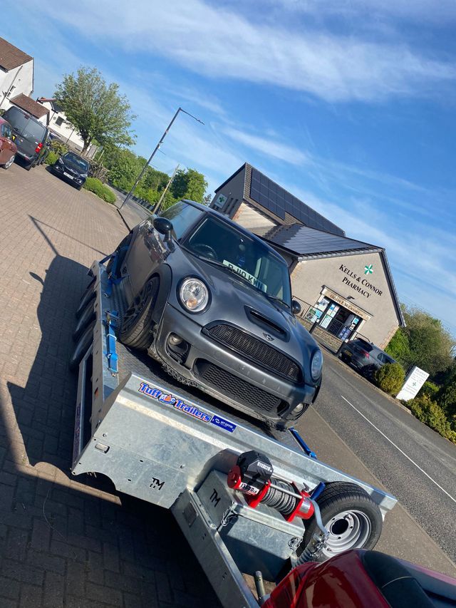 An unwanted car is being towed on a trailer on its way to be professionally disposed of.
