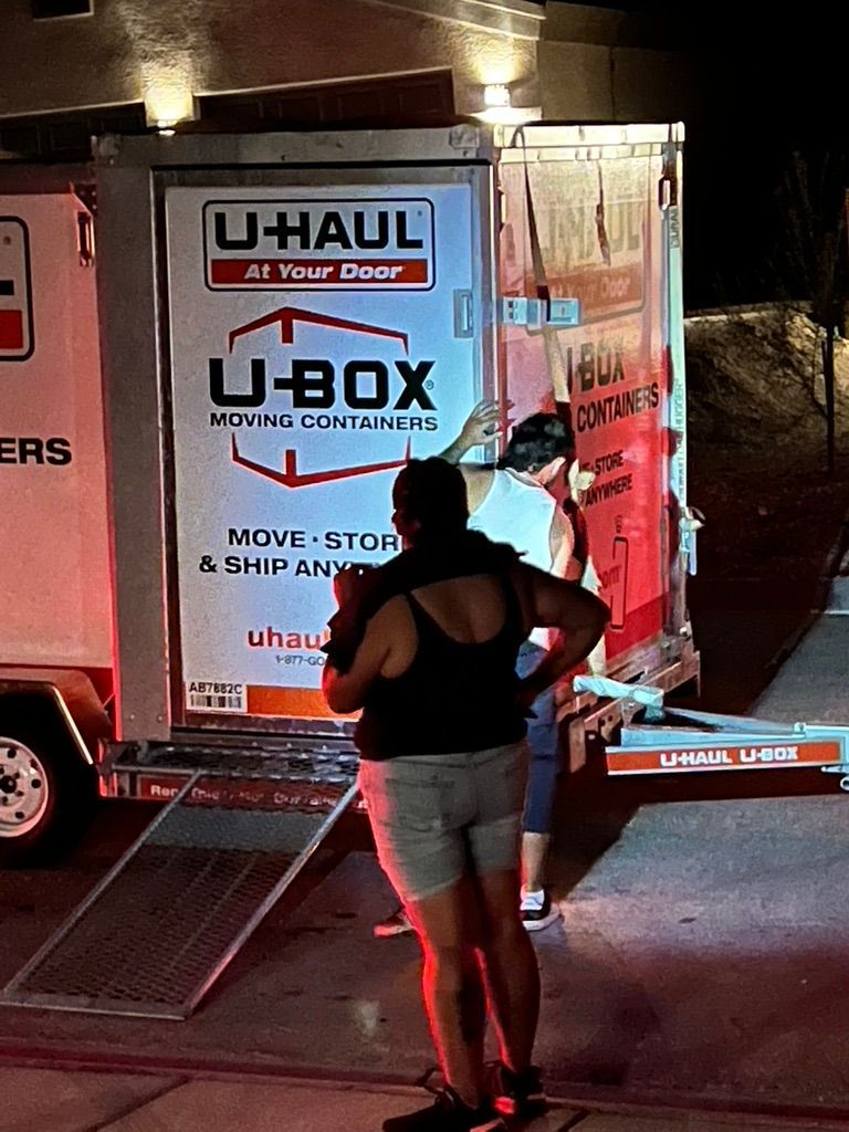 A woman is standing in front of a u-haul truck