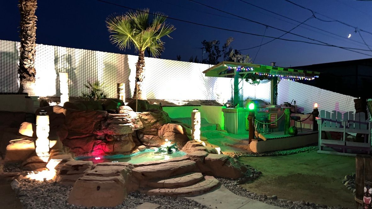 A backyard with a pool and a gazebo at night.
