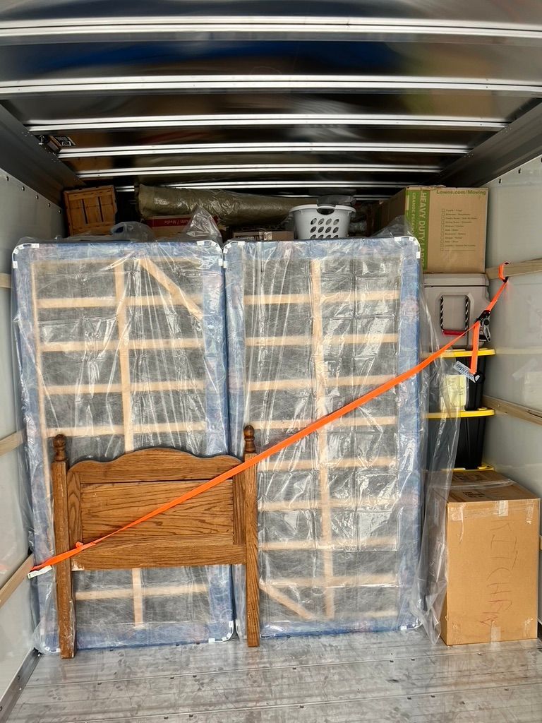 A truck filled with boxes , mattresses , and a bed.